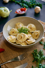 Delicious Plate of Dumplings Topped with Fresh Herbs and Accompanied by Sauces, Perfect for a Satisfying Meal Experience