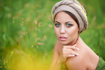 A charming woman is sitting in a field flooded with sunlight. Her eyes are the color of heavenly...