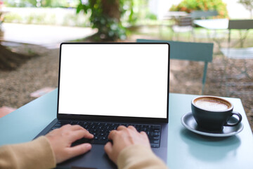 Mockup image of a woman working and typing on laptop computer with blank white desktop screen in...