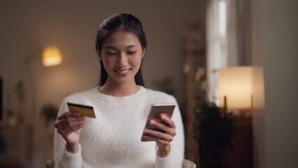 Asian young adult woman happily shops online with credit card at home for secure transactions and convenient lifestyle