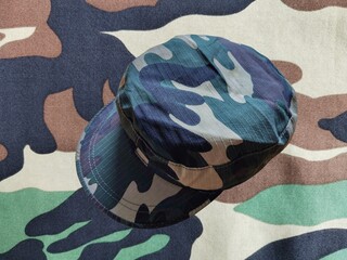 Camouflage military cap on a camouflage cloth background.
