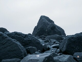 Dramatic Landscape of Jagged Dark Rocks Towering Against a Gray Sky with a Rugged Terrain