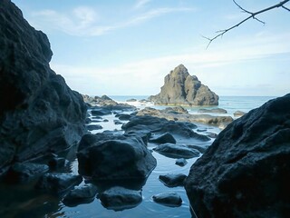 View Through Rock Formations Leading to a Distant Island Surrounded by Calm Waters Under a Clear Sky