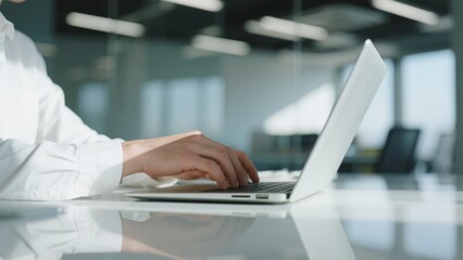 Person typing on a laptop in a modern office setting