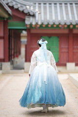 In June in Seoul, a Korean woman in her twenties stands regally by a wooden pillar at Gyeongbokgung...