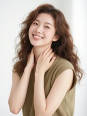 Fototapeta premium A person with wavy hair gently touching their neck, wearing a sleeveless olive top against a bright background.