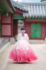 In Seoul in June 2025, two Korean women in their twenties wearing pink and sky-blue hanbok stand in...