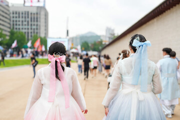 In June in Seoul, two Korean women in their thirties chat amid a bustling crowd at Gyeongbokgung...