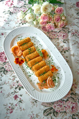 Delicious Golden Crispy Croquettes Arranged Elegantly on a White Platter Surrounded by Fresh Garnishes and a Floral Backdrop
