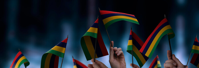 Mauritius flags in their hands on a blurred urban background