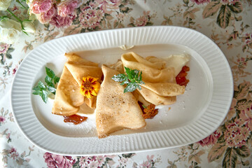 A Beautifully Plated Delicacy of Thin Pancakes with Fresh Mint and Vibrant Floral Garnish,...