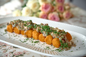 Delicious Dish Featuring Golden Croquettes Topped with Creamy Mushroom Gravy and Fresh Green Herbs...