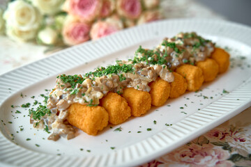 A Delightful Platter of Crispy Golden Nuggets Topped with Savory Mushroom Sauce and Fresh Herbs, Perfect for Any Gourmet Meal or Special Occasion.