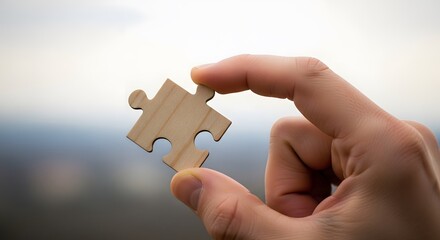Hand holding a single jigsaw puzzle piece against a blurred background. Concept of solution, connection, strategy, and finding the missing part for a problem.