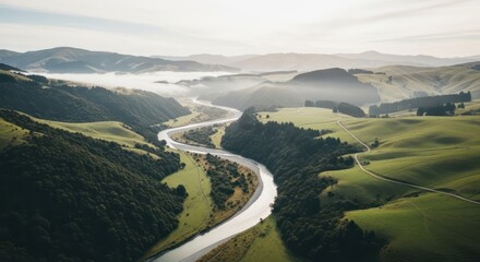 Winding river flows through green hills and misty mountains