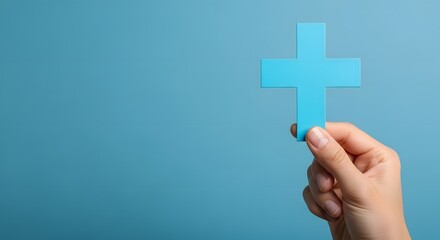 Obraz premium A hand holding a blue plus sign symbol against a solid blue background. Represents healthcare, medical aid, positive thinking, and addition.