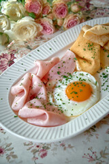 Delicious Plate of Ham Slices, a Fried Egg, and Crispy Pancakes Garnished with Fresh Herbs on a...
