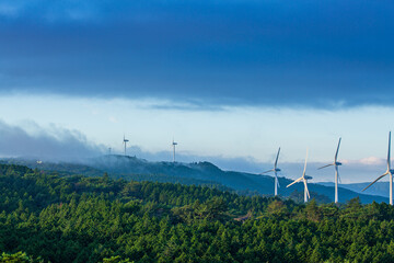  Wind turbines in a mountain range with mist at dusk