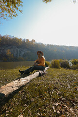 Blonde woman playing string guitar outdoors in autumn forest. Concept of sound therapy, mental...