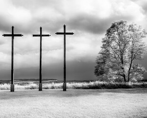 Three wooden crosses against a stormy sky. Black and white photo