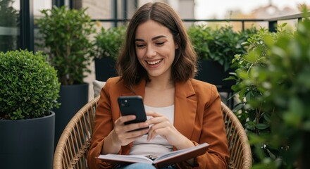 A young woman smiles as she uses her smartphone while sitting in a wicker chair on a balcony surrounded by lush greenery