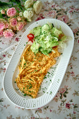 A Delightful Omelette Dish Served with Fresh Lettuce and Cherry Tomatoes, Surrounded by Beautiful Floral Accents on a Charming Table Setting