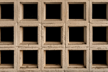 Close-up texture of a concrete ventilation block wall (roster), creating a geometric grid pattern...