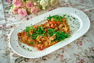 Delicious Savory Omelette Topped with Fresh Vegetables, Herbs, and Garnish, Perfect for a Healthy Breakfast or Lunch on a Floral Table Setting