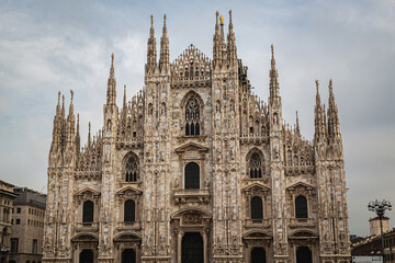 The Milan Cathedral (Duomo di Milano) captured in daylight from the front, showcasing its stunning Gothic architecture with intricate spires and statues under a cloudy sky using landscape photography 