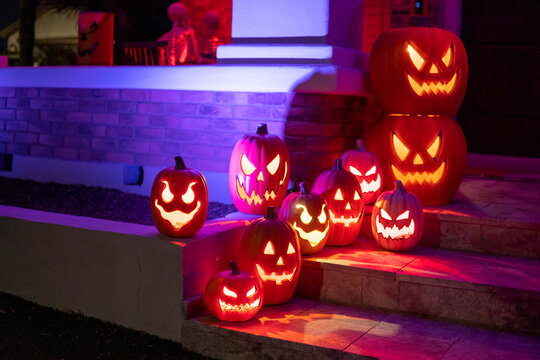 Halloween pumpkin lantern with candles on the house stairs. lowing angry pumpkins at night. Halloween outdoor decor. Scary pumpkins faces