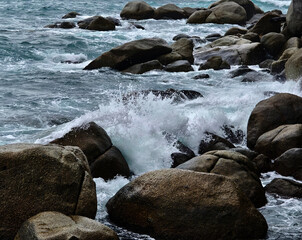 The powerful waves are forcefully crashing against the rocks in the vast ocean