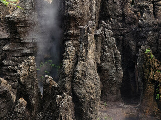 A beautiful waterfall is surrounded by numerous rocks and lush trees