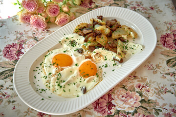 A Beautifully Arranged Breakfast Plate Featuring Perfectly Cooked Eggs and Seasoned Potatoes Surrounded by a Charming Floral Table Setting