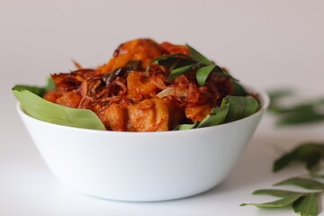 Chicken Peralan, Kerala style dry roasted chicken, served in a banana leaf lined white bowl