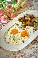 Deliciously Prepared Eggs with Golden Yolks Served Alongside Flavorful Roasted Potatoes and Garnished with Fresh Herbs on an Elegant Floral Table Setting