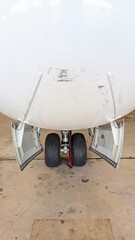 Close-up view of an aircraft nose landing gear with open gear doors inside a hangar