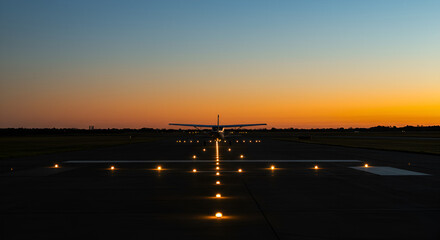 Airplane on the runway at dusk prepares for take off to the scenic sunset