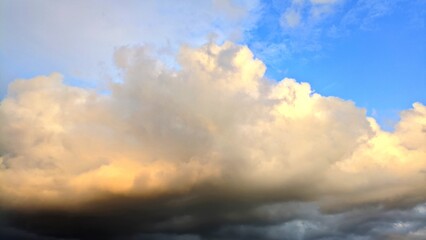 Naklejka premium Dramatic cloudy sky with soft golden sunlight breaking through layers of thick evening clouds