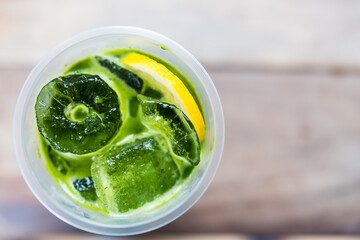 A glass of cold green tea in a glass filled with ice and a slice of lime
