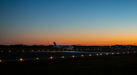 Single-Engine Plane on Runway at Dusk with Beautiful Sky Background and Lights