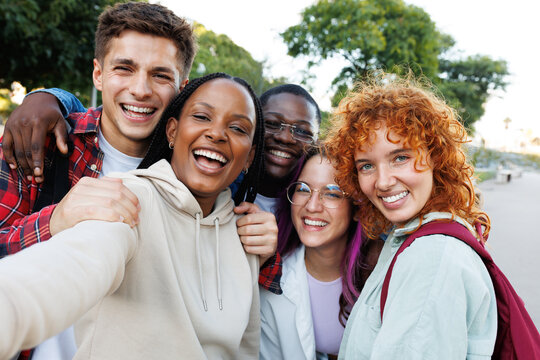 Happy diverse students taking a selfie outdoors smiling and hugging