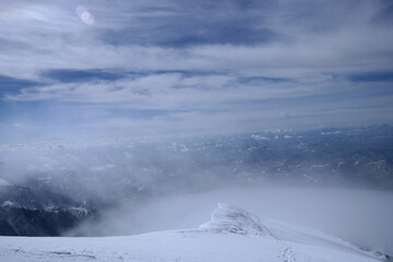 A stunning rock formation covered in snow, set against a clear blue sky with fluffy clouds in the background, creating a peaceful and breathtaking mountain landscape.