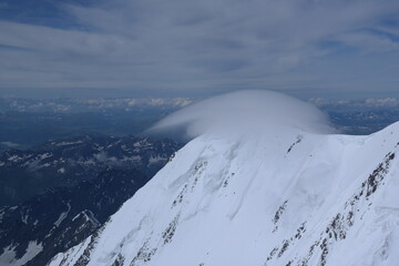 A stunning rock formation covered in snow, set against a clear blue sky with fluffy clouds in the...