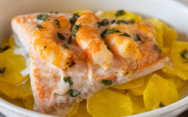 Salmon fillet cooked with shrimps and potatoes in a creamy white sauce, garnished with fresh herbs,...