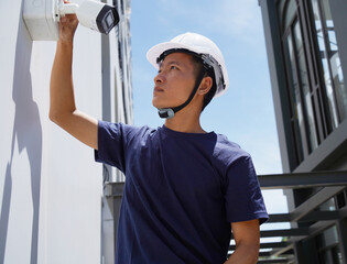 A technician installs a CCTV camera on the facade of a residential building