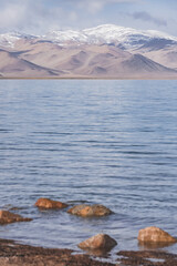 Panorama landscape of Lake Karakul in the Pamir mountains in the Tien Shan against the background of high snowy rocky peaks with clouds, morning panorama of the lake for the background