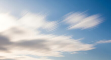 Abstract motion blur of white clouds against a bright blue sky