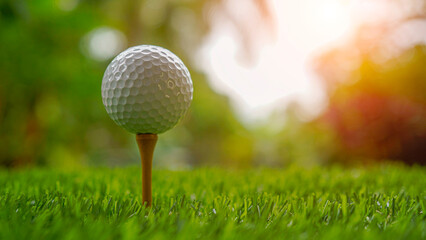 Golf ball on tee in beautiful golf course with sunset.