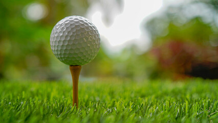 Golf ball on tee in beautiful golf course with sunset.