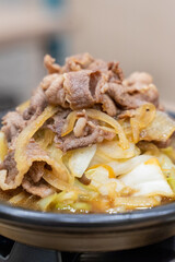A traditional Asian clay pot rice dish is served piping hot, nestled in a rustic earthenware pot. Steam rises from the sizzling surface, revealing layers of tender sliced meat, crisp bean sprouts